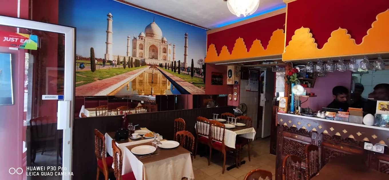 La salle du restaurant, ses tables dressées et sa grande fresque du Taj Mahal